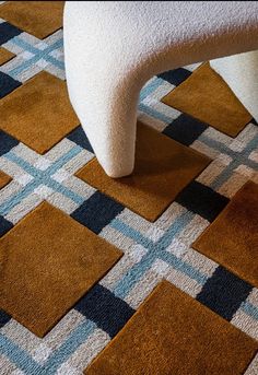 a white chair sitting on top of a checkered floor next to a brown and blue rug