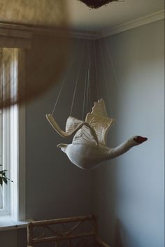 a white bird hanging from the ceiling next to a window