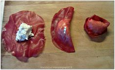 two pieces of meat on a cutting board with blue cheese in the middle, and another piece of meat that has been cut into smaller pieces