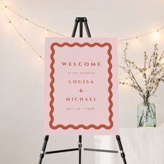 a welcome sign is on an easel in front of a string of christmas lights