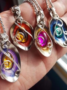 four different colored glass pendants on a person's hand