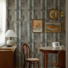 two chairs and a table in front of a striped wallpapered room with pictures on the walls