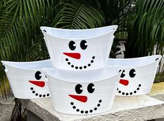 four white buckets with faces painted on them