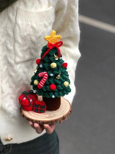 a person holding a small christmas tree on a piece of wood