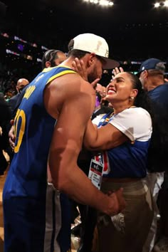 a man and woman embracing each other at a basketball game