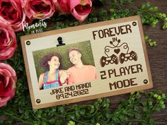 a wooden photo frame with the words forever in e - player mode on it next to flowers