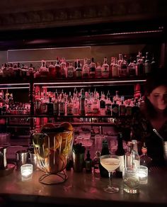 a woman sitting at a bar with lots of bottles and glasses