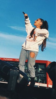 a woman standing on the back of a red truck holding a cell phone in her hand