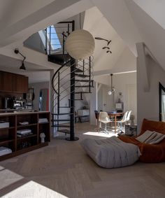 a spiral staircase in the middle of a living room with an orange chair and ottoman