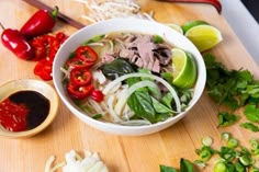 a wooden cutting board topped with a bowl of soup next to sliced onions and peppers