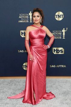 a woman in a red dress posing for the camera at an awards event with her hands on her hips