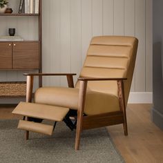 a recliner chair and footstool in front of a shelf with books on it