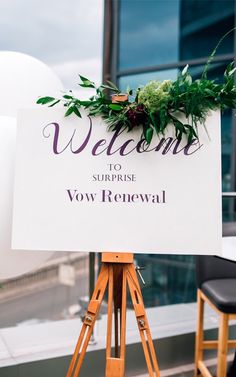 a welcome sign sitting on top of a wooden easel in front of a building