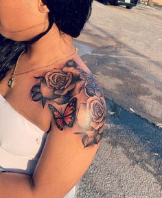 a woman with a butterfly and roses tattoo on her arm, holding onto the shoulder