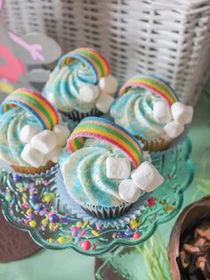 cupcakes with rainbow frosting and marshmallows are on a plate