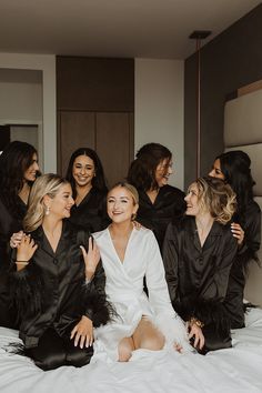 a group of women sitting on top of a bed next to each other in black robes