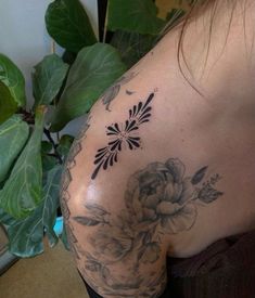 a woman's shoulder with flowers and leaves on her back, in front of a potted plant