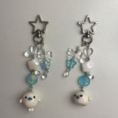 two white and blue earrings with charms hanging from them