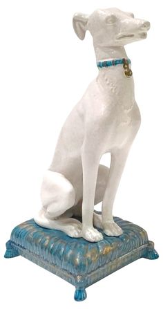 a white dog statue sitting on top of a blue cushion