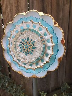 a blue and white glass plate sitting on top of a wooden table next to a fence