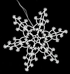 a white snowflake on a black background with some strings hanging from it's center