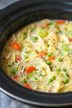 a crock pot filled with chicken noodle soup and carrots, celery