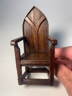 a miniature wooden chair being held by a hand