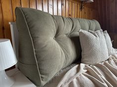 a bed with two pillows on top of it next to a night stand and lamp