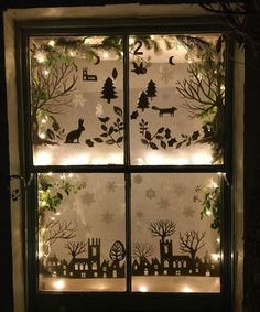 a window decorated with christmas lights and paper cut animals in the winter scene outside it