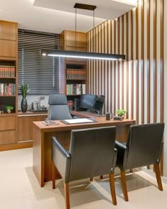 an office with two desks and chairs in front of a bookcase filled with books