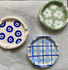 three plates with blue and white designs on them sitting next to each other in the shape of eyes