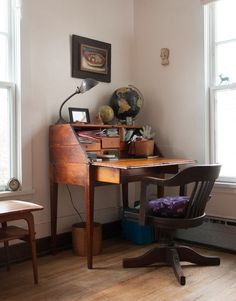 a desk with a chair, lamp and pictures on the wall