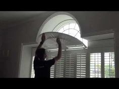 a man holding an umbrella over his head in front of a window with shutters