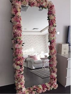 a mirror that has flowers on it in front of a room with a couch and table