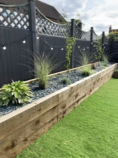 a wooden planter filled with plants next to a fence