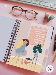 an open notebook sitting on top of a pink desk next to a keyboard and glasses