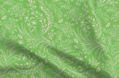 a green and white paisley print fabric with small flowers on the bottom half of it