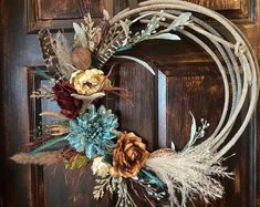 a wreath with feathers and flowers is hanging on the front door to give it a rustic feel