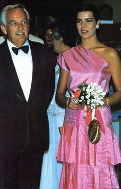 an older man in a tuxedo standing next to a woman in a pink dress