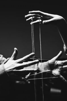 two hands reaching for strings attached to each other