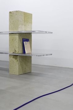 a book shelf with two books on it in an empty room next to a wall