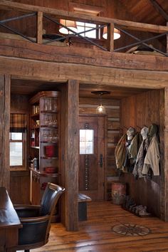 the inside of a log cabin with wood floors and walls, coat racks on the wall