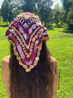 the back of a woman's head wearing a crocheted hat in a field