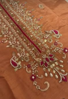 an embroidered fabric with gold and red beads on it's edges, along with other beaded details