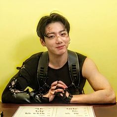 a man sitting at a table with his hands on his chest and wearing leather gloves