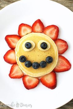 a pancake with strawberries and blueberries in the shape of a face