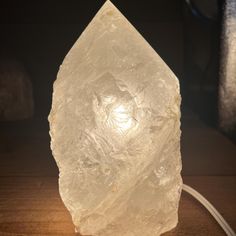 a large white rock sitting on top of a wooden table next to a light bulb