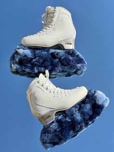 there are two pairs of white shoes on top of blue fluffy material in the air