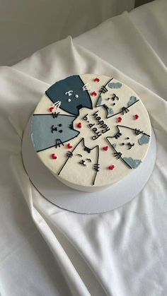 a white cake with blue frosting on top of a white sheet covered tablecloth