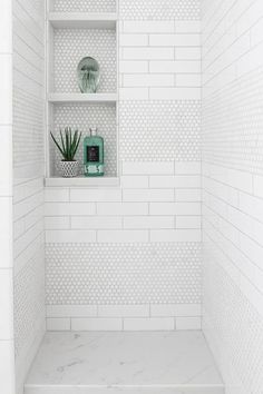 a white tiled shower with shelves and plants